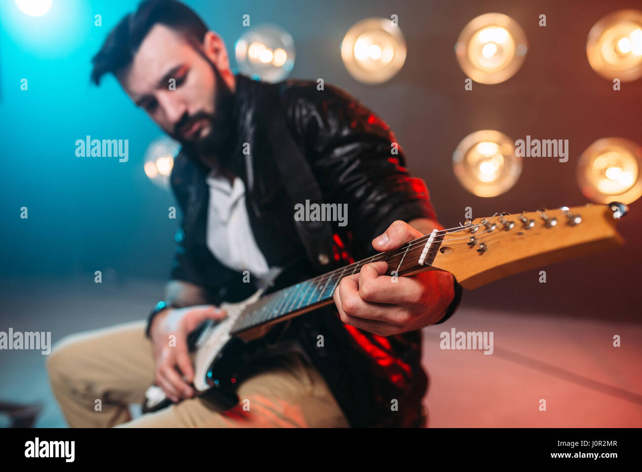 Musican Male solo avec guitare électro sur la scène avec les décors de lumières. Music Entertainment. Banque D'Images