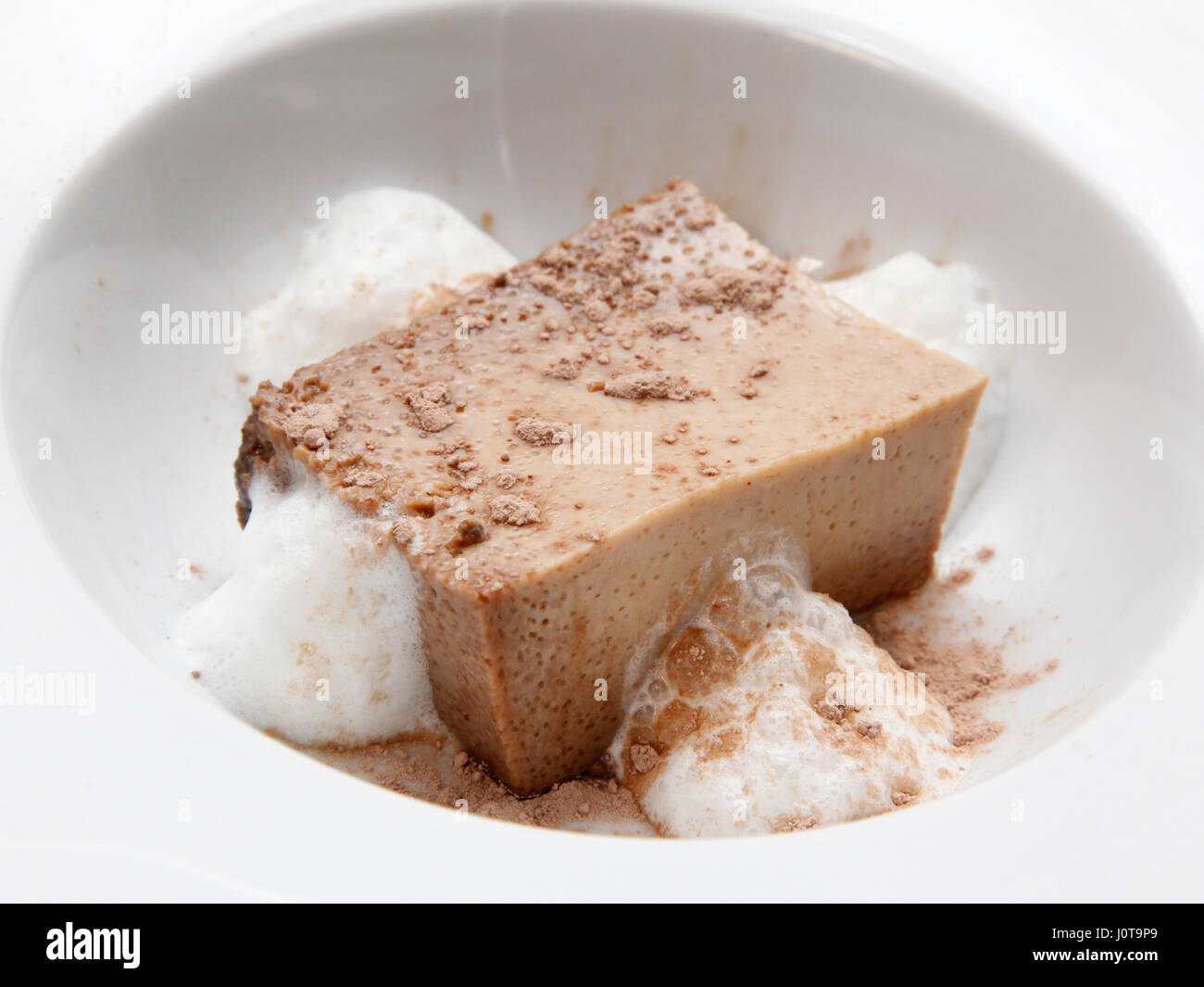Un individu plum-pudding surmontée de la poudre de cacao et entouré de mousse à la crème Banque D'Images