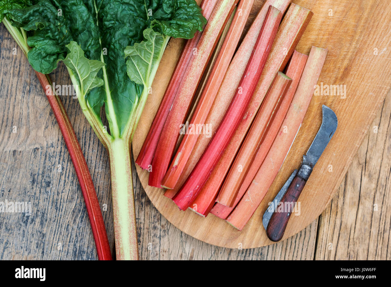 Rheum rhabarbarum. Les bâtonnets de rhubarbe récoltée sur une planche en bois Banque D'Images