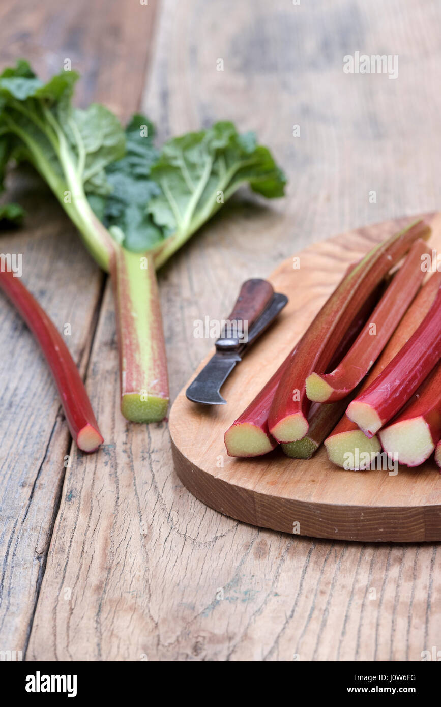Rheum rhabarbarum. Les bâtonnets de rhubarbe récoltée sur une planche en bois Banque D'Images