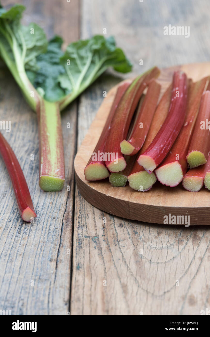 Rheum rhabarbarum. Les bâtonnets de rhubarbe récoltée sur une planche en bois Banque D'Images