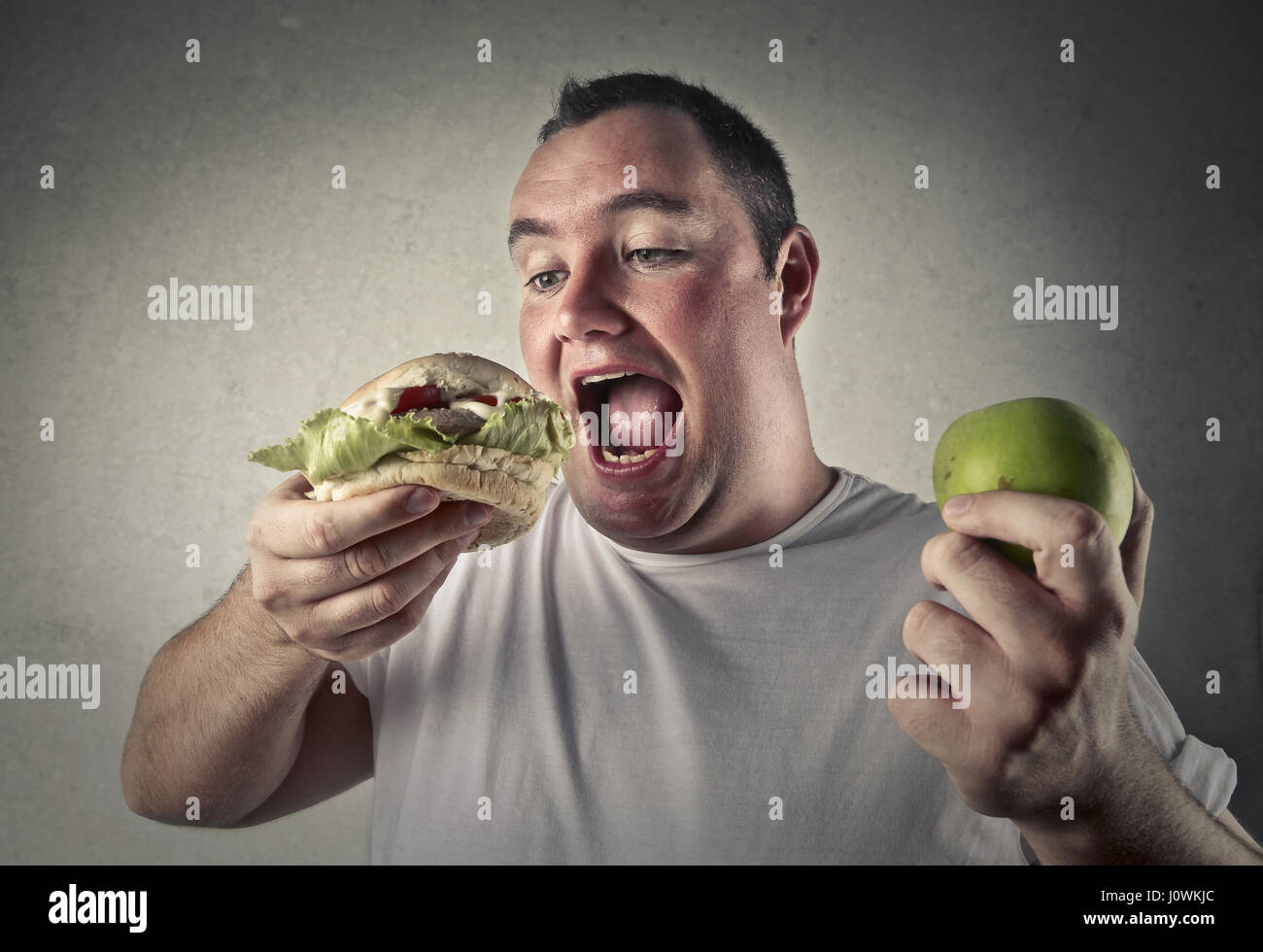 L'homme obèse eating hamburger au lieu d'apple Banque D'Images