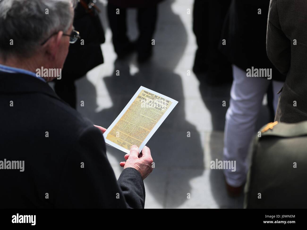 Un membre du public lit une copie de la Proclamation au cours d'une cérémonie pour marquer le 101e anniversaire de la Pâques 1916 qui se lève devant l'GPO, dans la rue O'Connell, Dublin. Banque D'Images