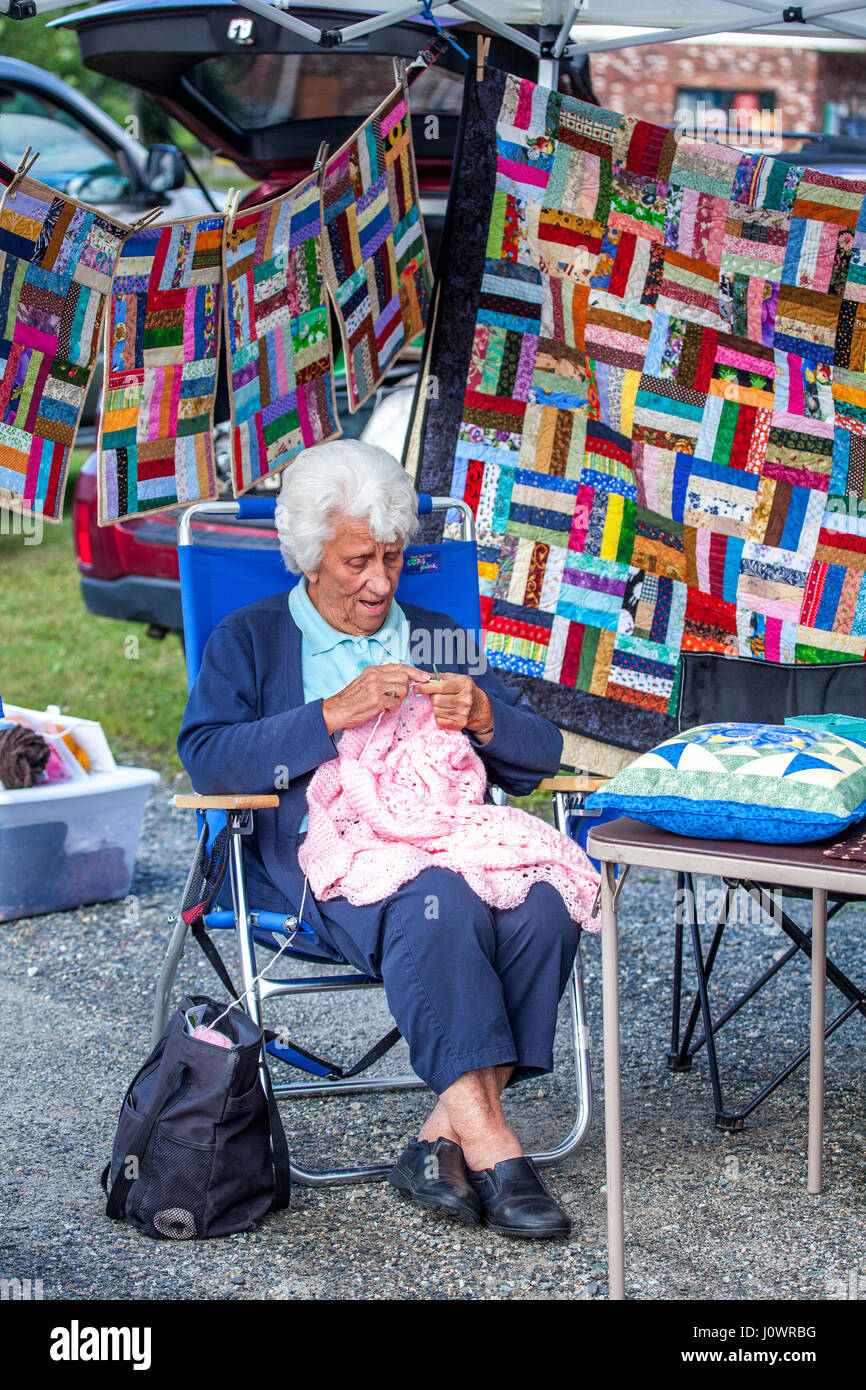 Une vieille dame aux cheveux blancs tricote un chandail rose à un marché en plein air aux États-Unis. Banque D'Images