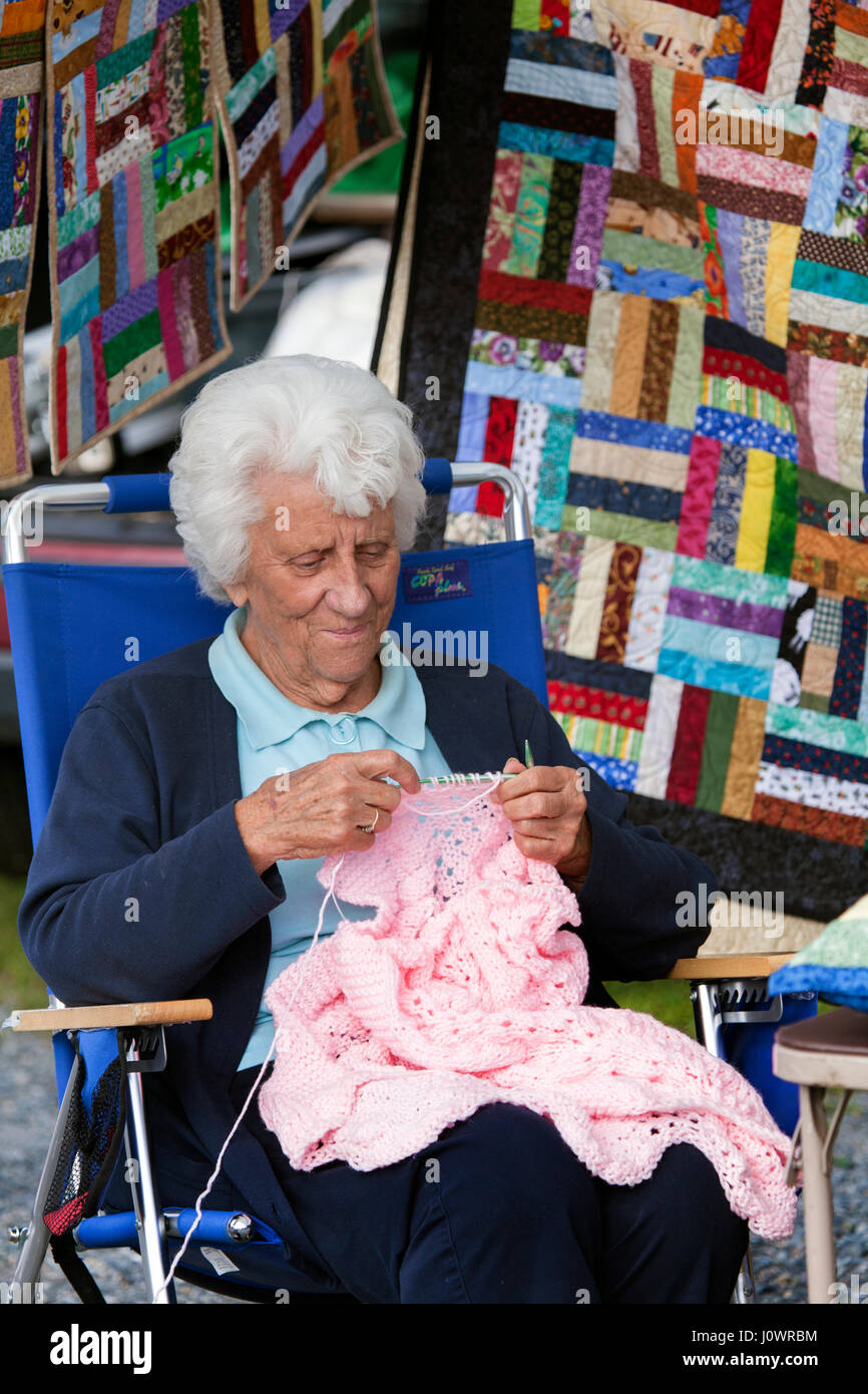 Un blanc-haired woman aime tricoter un chandail rose au marché de producteurs à Lisbonne, New Hampshire, United States. Banque D'Images