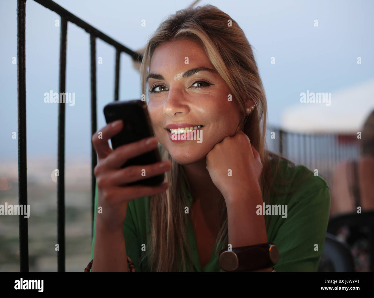 Woman smiling avec son téléphone à l'extérieur Banque D'Images