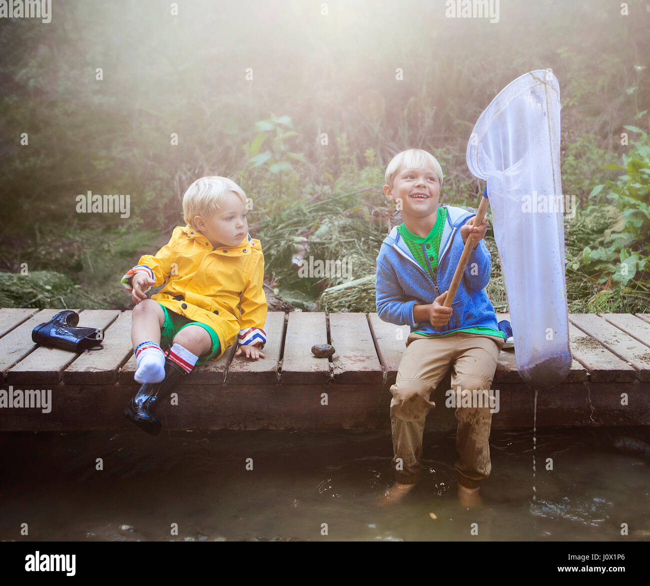 Deux garçons assis sur la pêche jetée en bois Banque D'Images