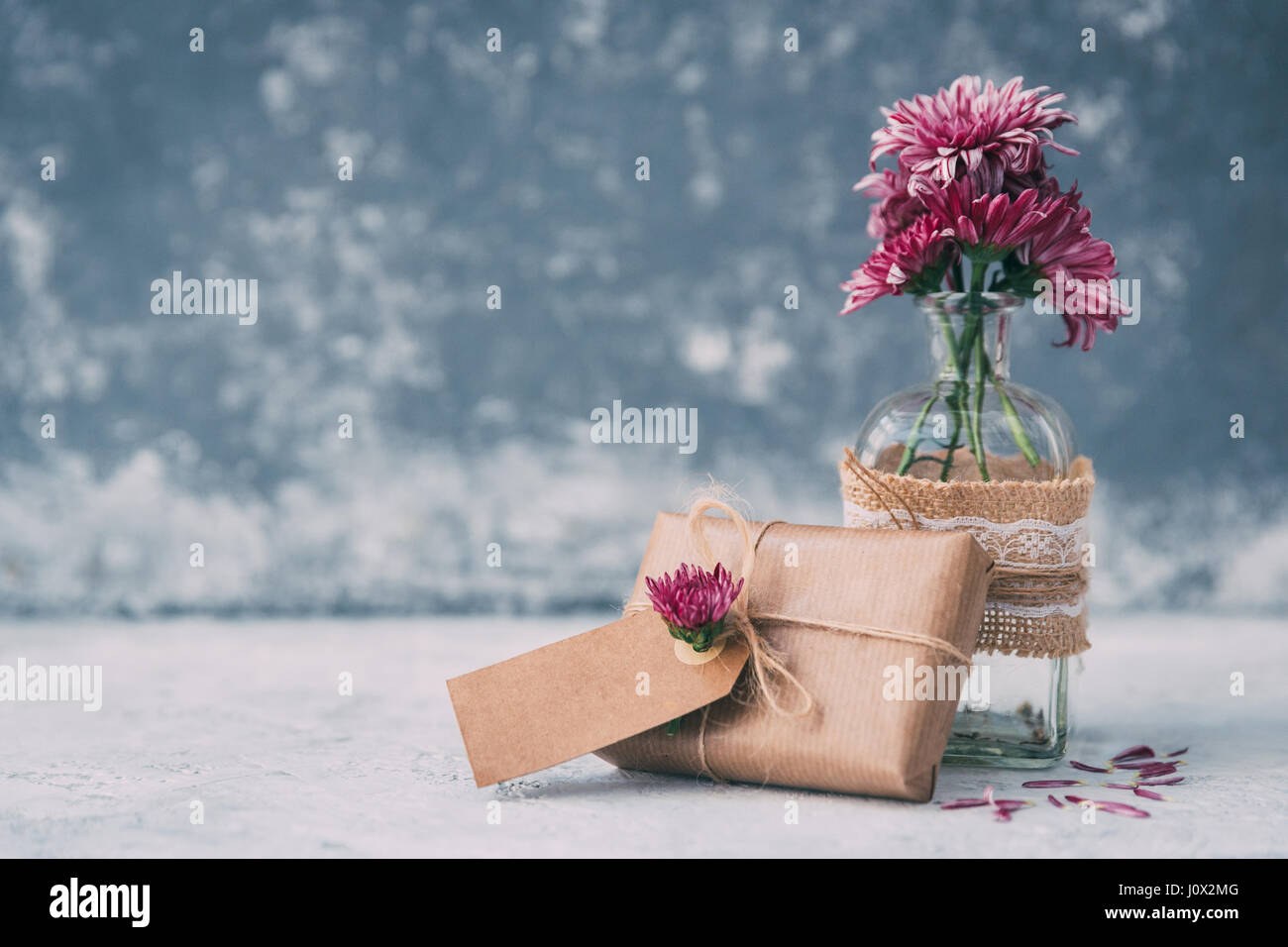 Boîte cadeau enveloppé et vase avec fleurs roses Banque D'Images