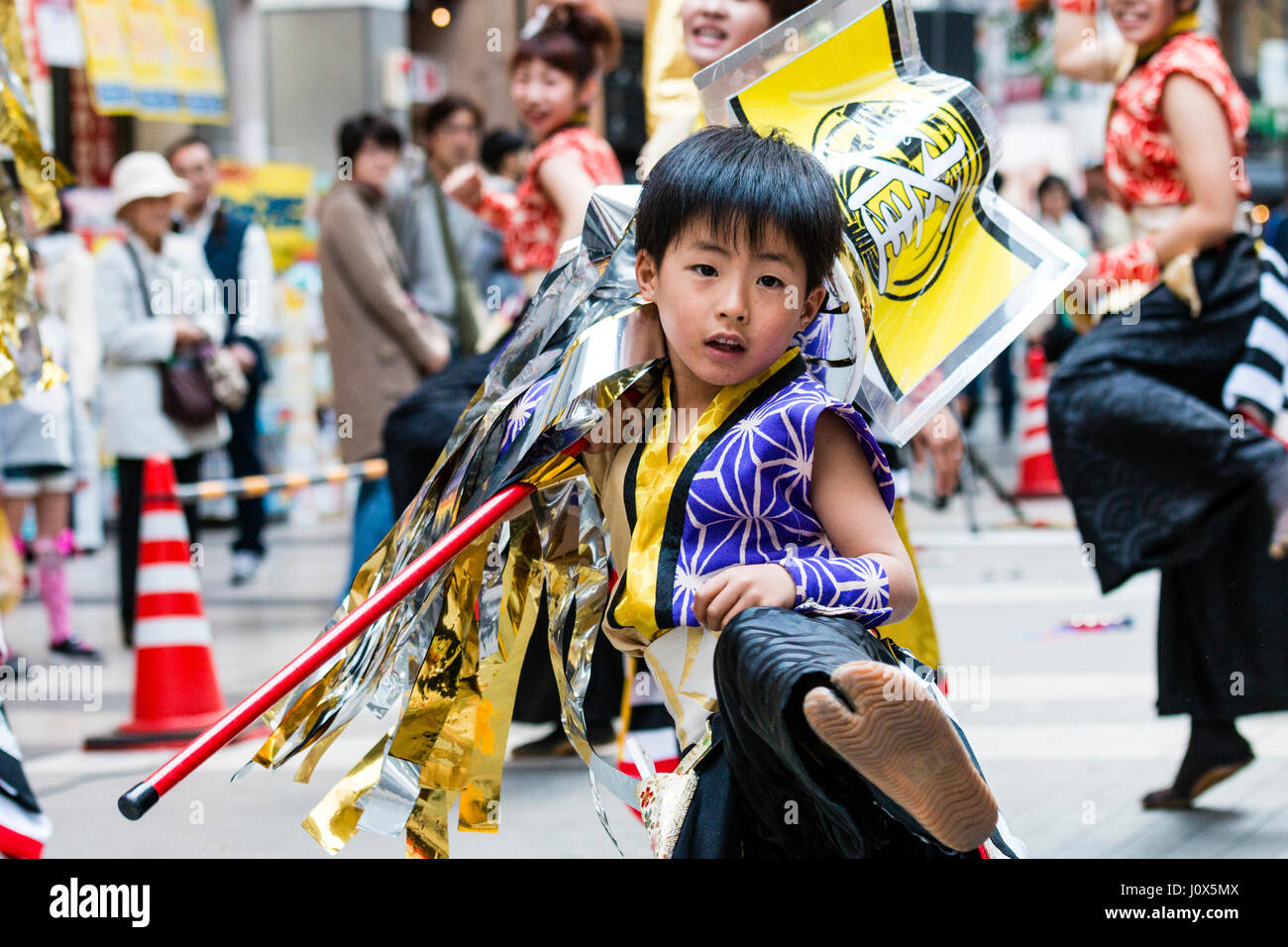 Le Japon, Kumamoto, Hinokuni Danse Yosakoi Festival. Enfant, garçon, 7-8 ans danse et forme autour de standard, les coups de pied vers viewer. close up. Banque D'Images
