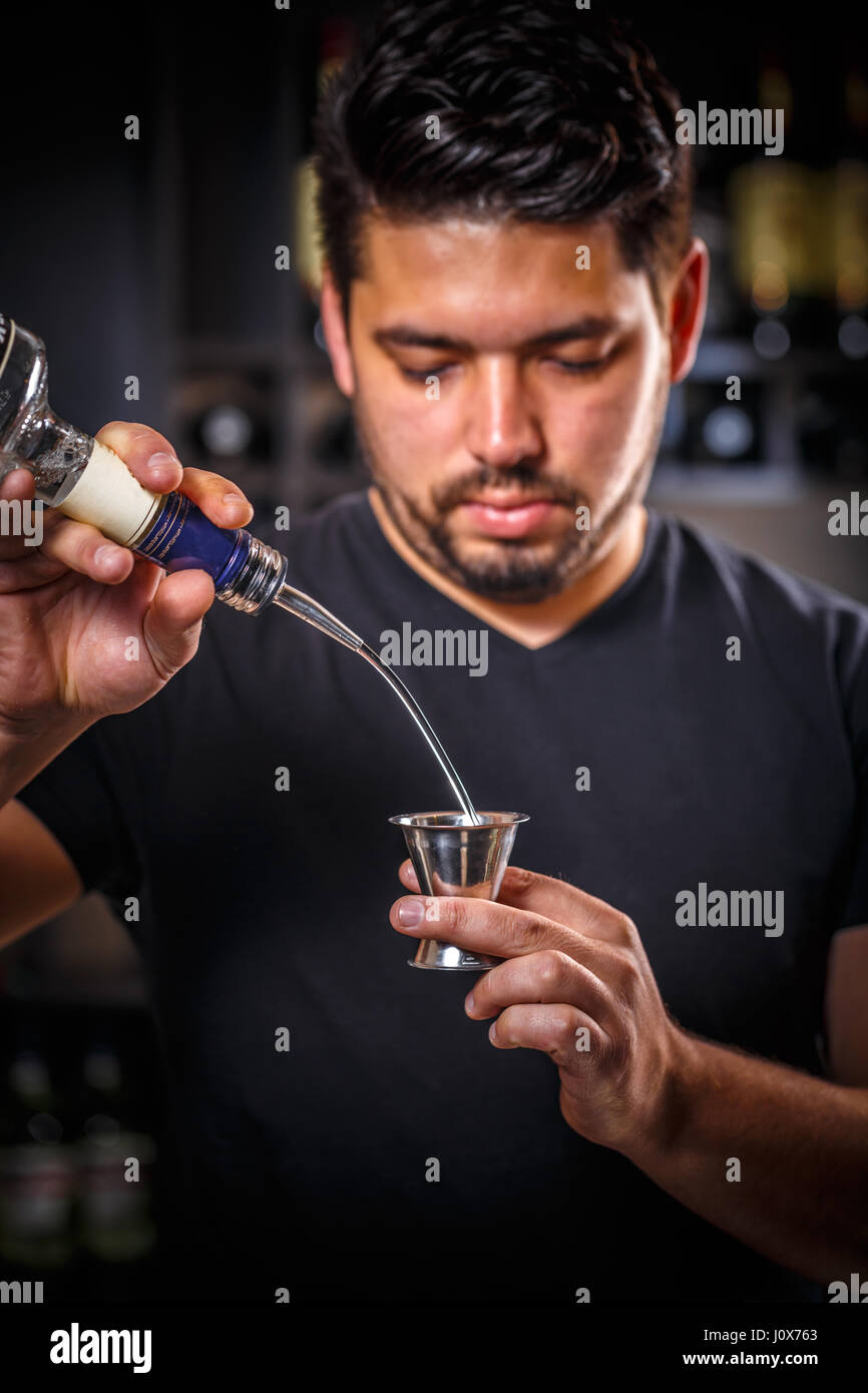 Barman professionnel au travail en versant un verre dans un bar en verre de mesure Banque D'Images