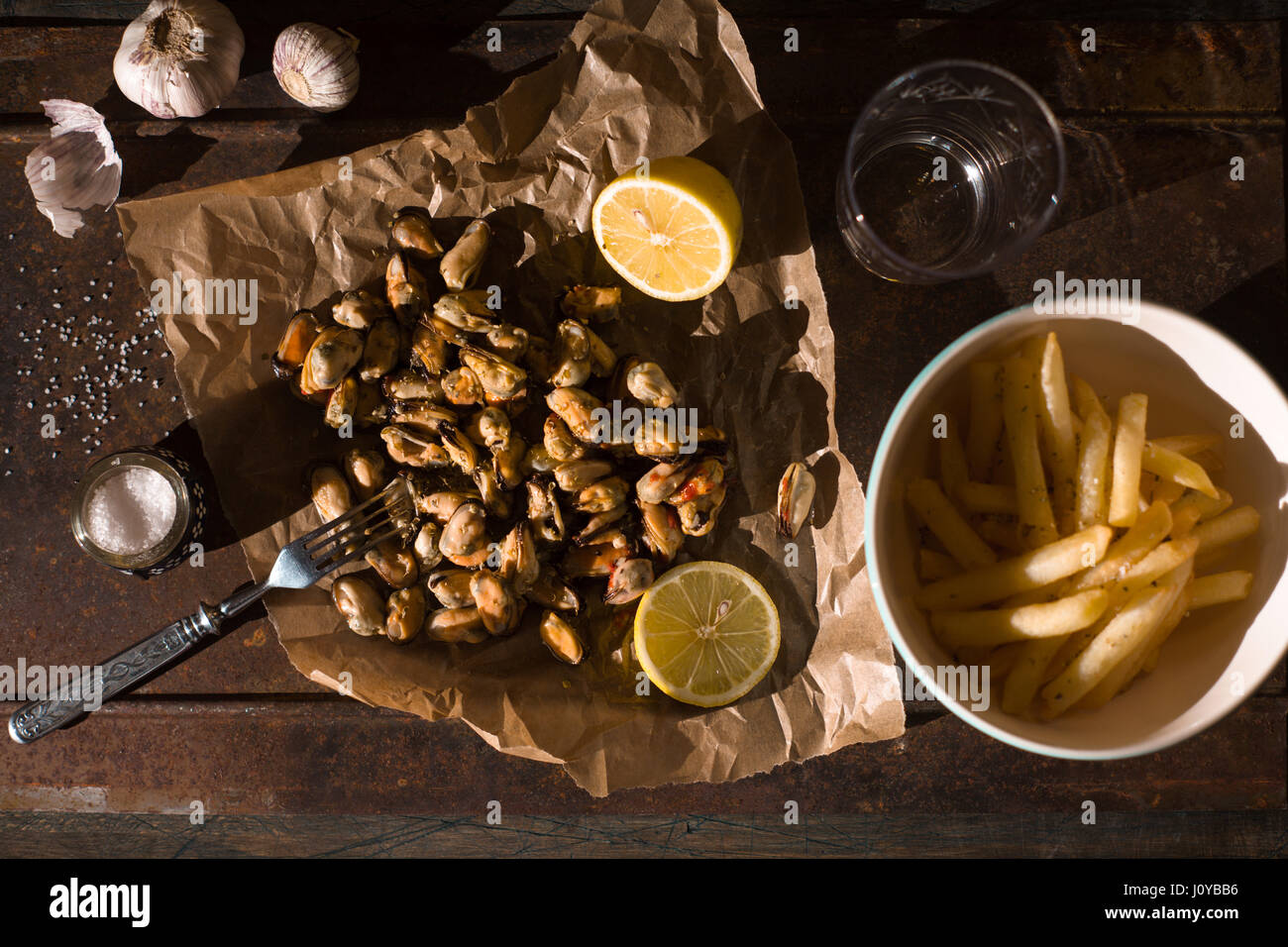 Les moules avec les citrons et les frites sur le fond métallique vue supérieure Banque D'Images