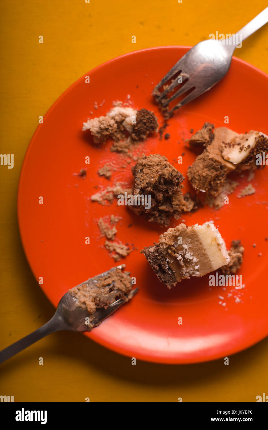 Morceaux de gâteau au chocolat avec des copeaux de noix de coco sur une plaque orange Banque D'Images