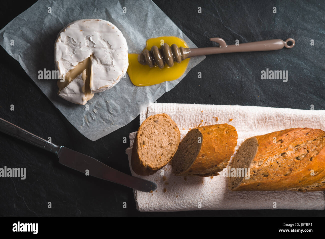 Fromage Brie, morceaux de pain baguette, du miel sur parchemin Banque D'Images