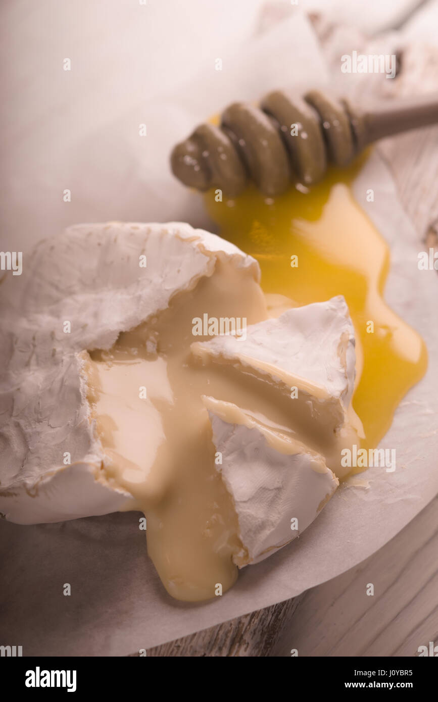Tranches de fromage Brie, miel, sur parchemin flou partiel Banque D'Images