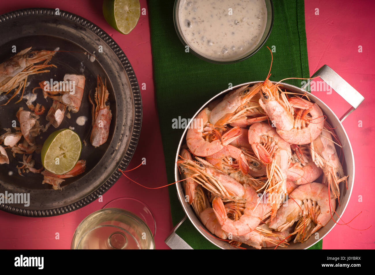 Crevettes sur une table rose, verre de vin blanc et de la sauce Banque D'Images
