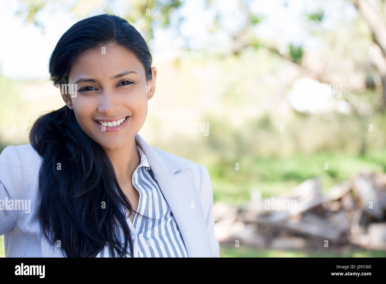 Closeup portrait of smiling happy jolie jeune femme en costume gris, les arbres isolés de l'arrière-plan flou. L'émotion positive expre faciale Banque D'Images Closeup portrait of smiling happy jolie jeune femme en costume gris, les arbres isolés de l'arrière-plan flou. L'émotion positive expre faciale Banque D'Images
