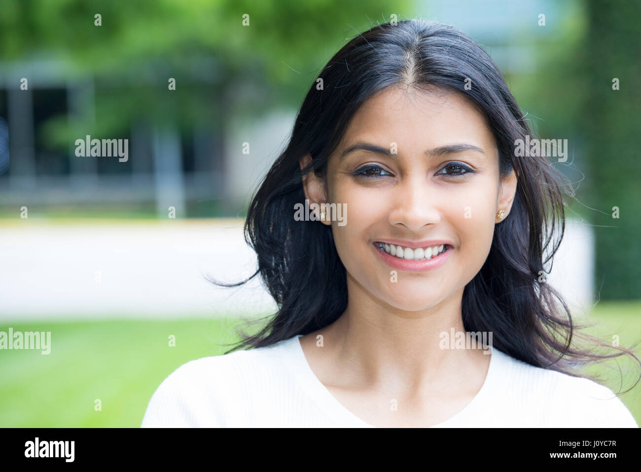 Closeup portrait of smiling happy jolie jeune femme en chemise blanche, isolée de l'arrière-plan flou des arbres. L'émotion positive exp faciale Banque D'Images Closeup portrait of smiling happy jolie jeune femme en chemise blanche, isolée de l'arrière-plan flou des arbres. L'émotion positive exp faciale Banque D'Images