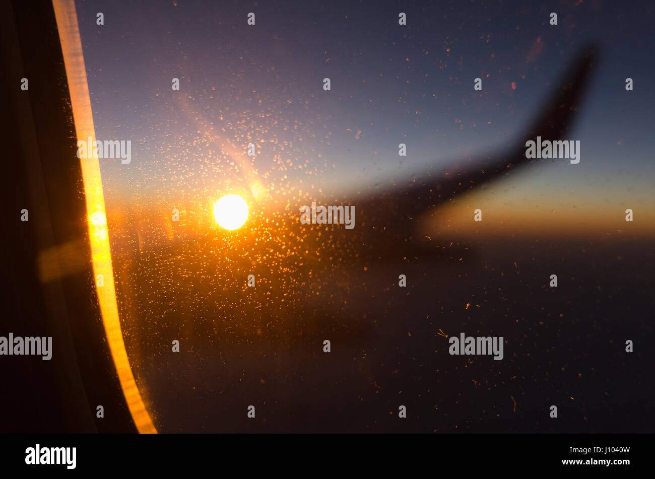 Une image abstraite de coucher de soleil derrière l'aile d'un avion, au moyen d'une fenêtre glacée Banque D'Images
