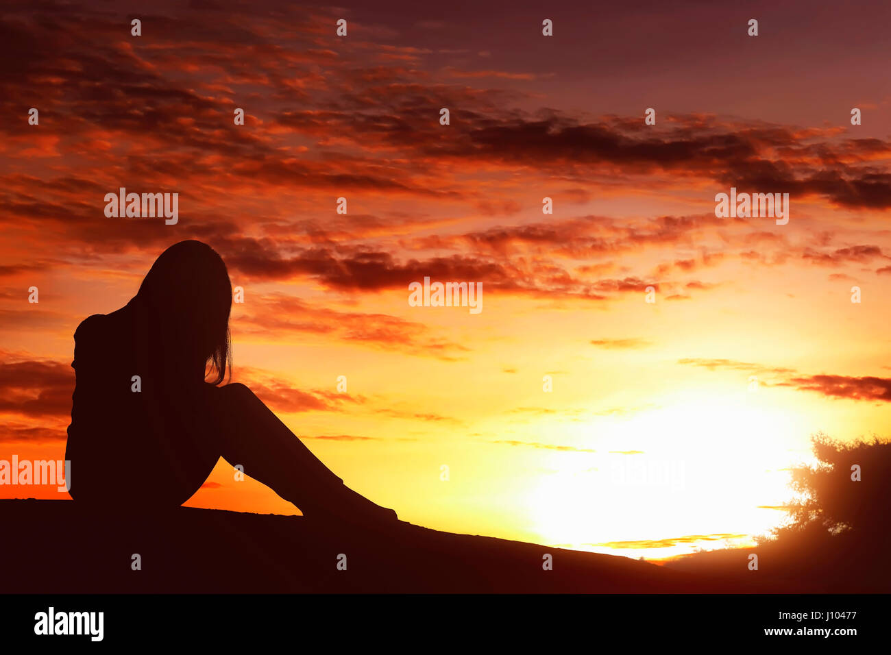 L'expression triste silhouette femme siégeant seul au sommet de la colline au coucher du soleil Banque D'Images