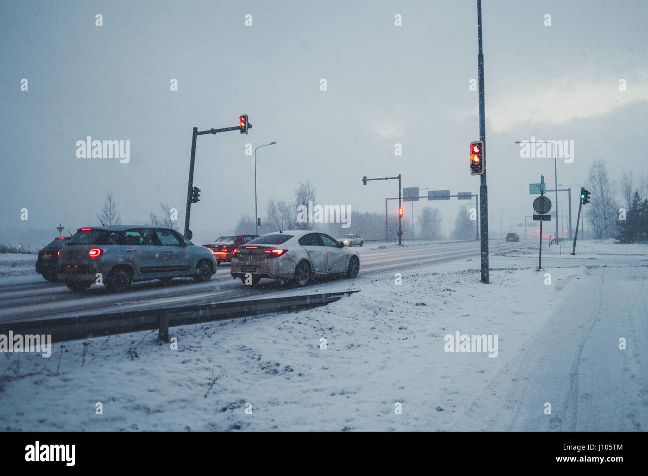 Dirty véhicules arrêtés sur feu sur jour de neige à Raisio, Finlande Banque D'Images