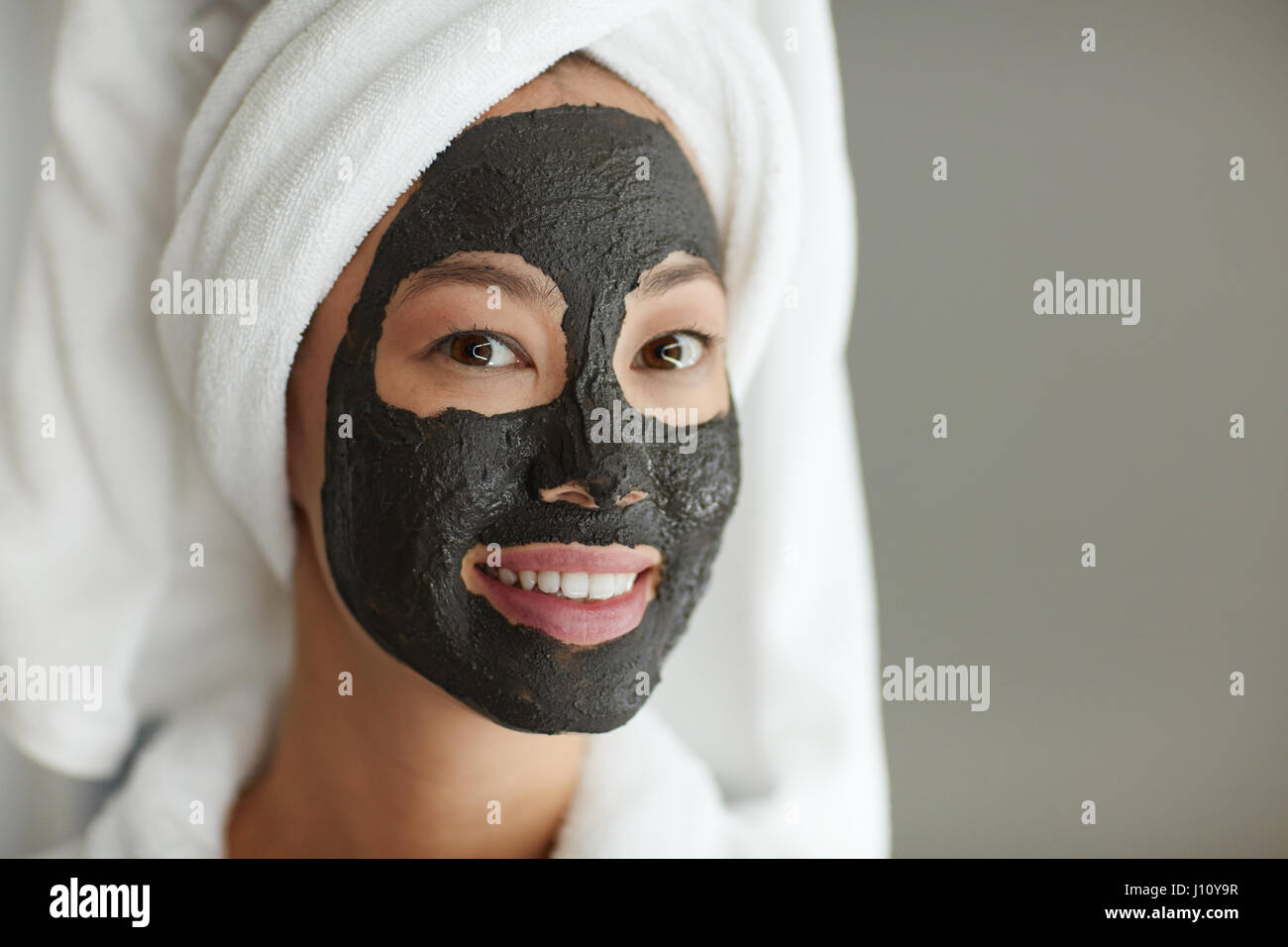 Jolie jeune fille avec masque de boue sur le visage et towel on head Banque D'Images
