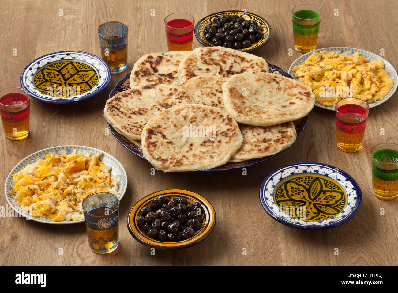 Petit-déjeuner traditionnel marocain avec des crêpes, œufs, olives noires, huile d'olive et le thé à la menthe Banque D'Images