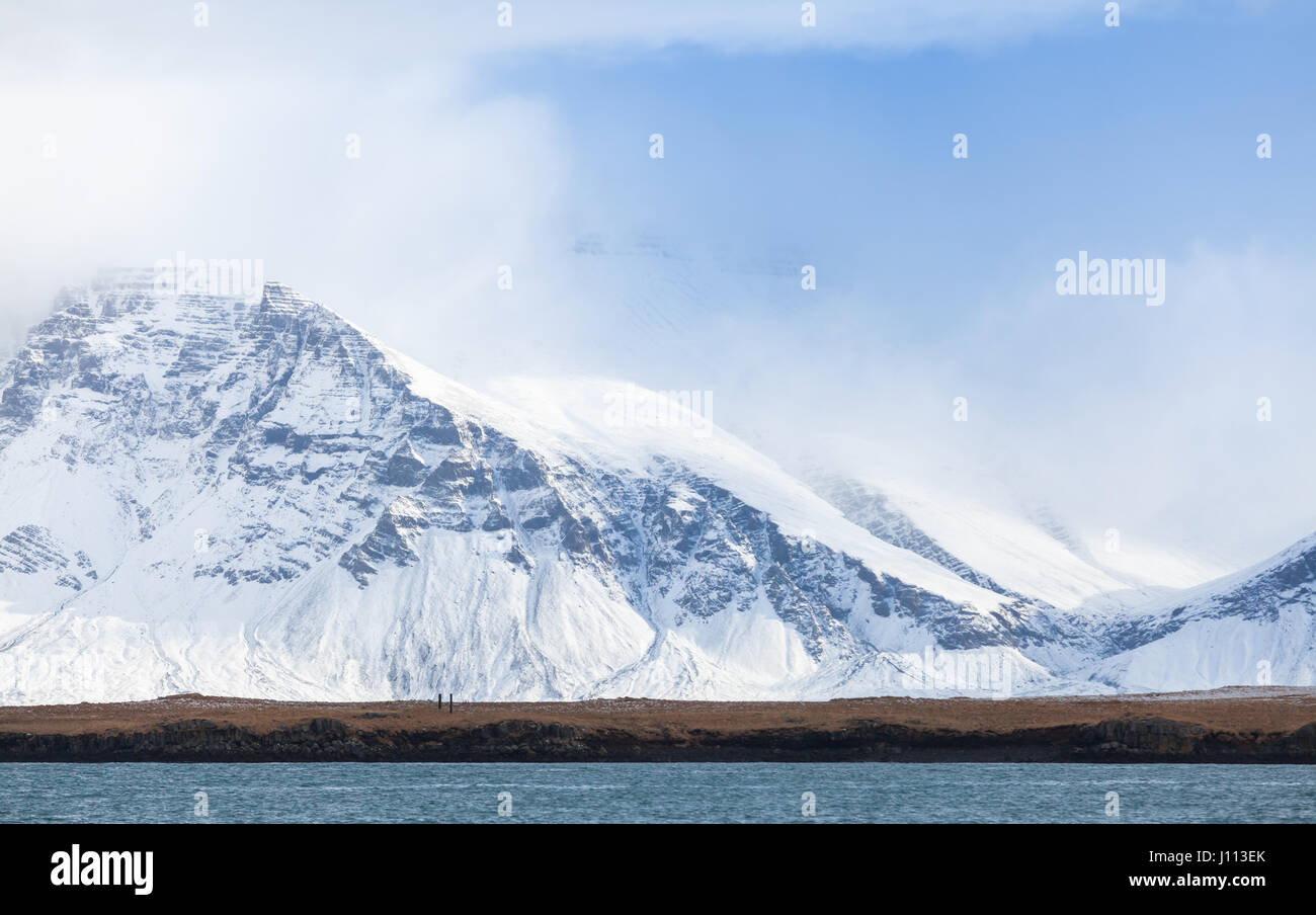 Paysage islandais côtières avec montagnes enneigées sous ciel nuageux. Région de Reykjavik, Islande Banque D'Images