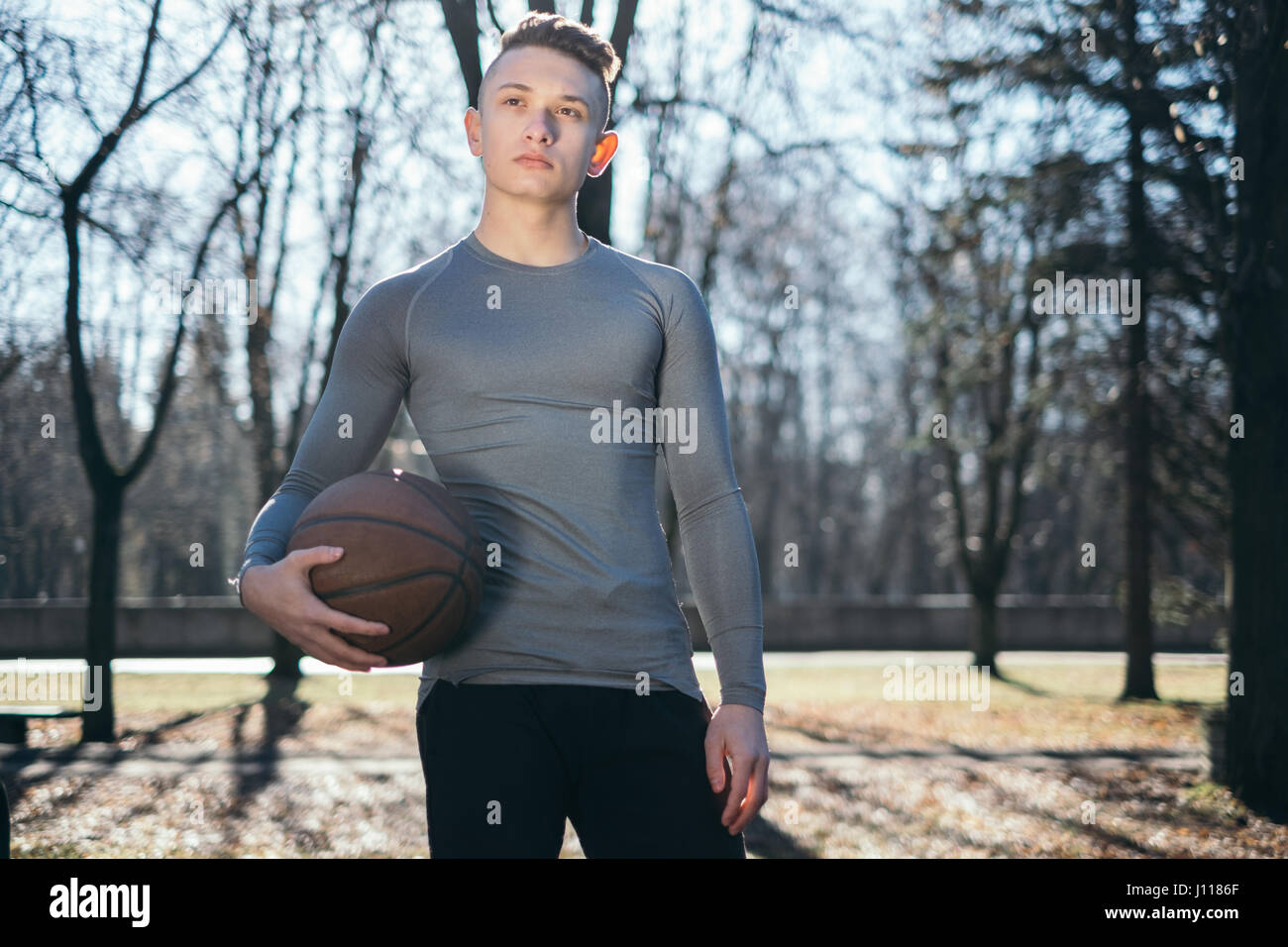 Man Standing in park holding basketball, Minsk, Bélarus Banque D'Images