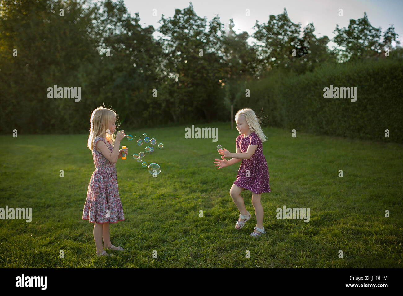 Deux jeunes filles faisant des bulles dans le jardin Banque D'Images