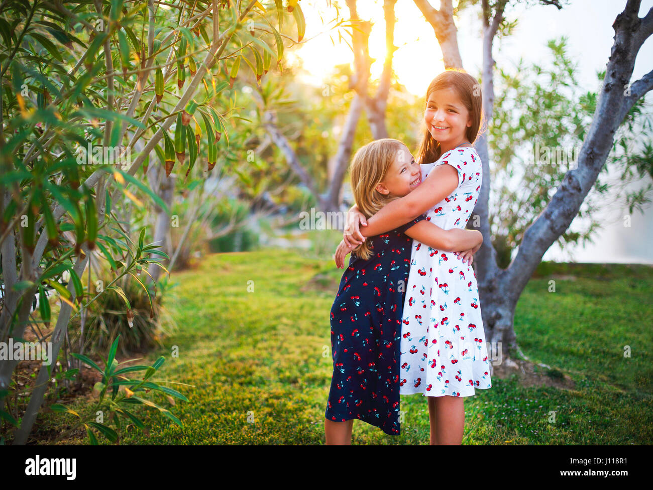 Happy funny soeurs embrasser ensemble dans l'heure du coucher du soleil Banque D'Images