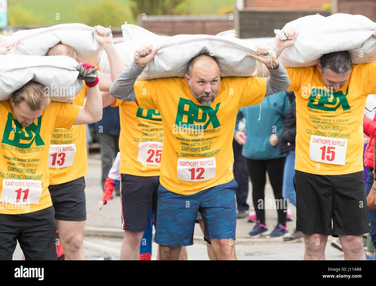 Les hommes portent des sacs de charbon comme ils sont en concurrence dans le monde de transport de charbon en Championnats Gawthorpe, Yorkshire. Banque D'Images