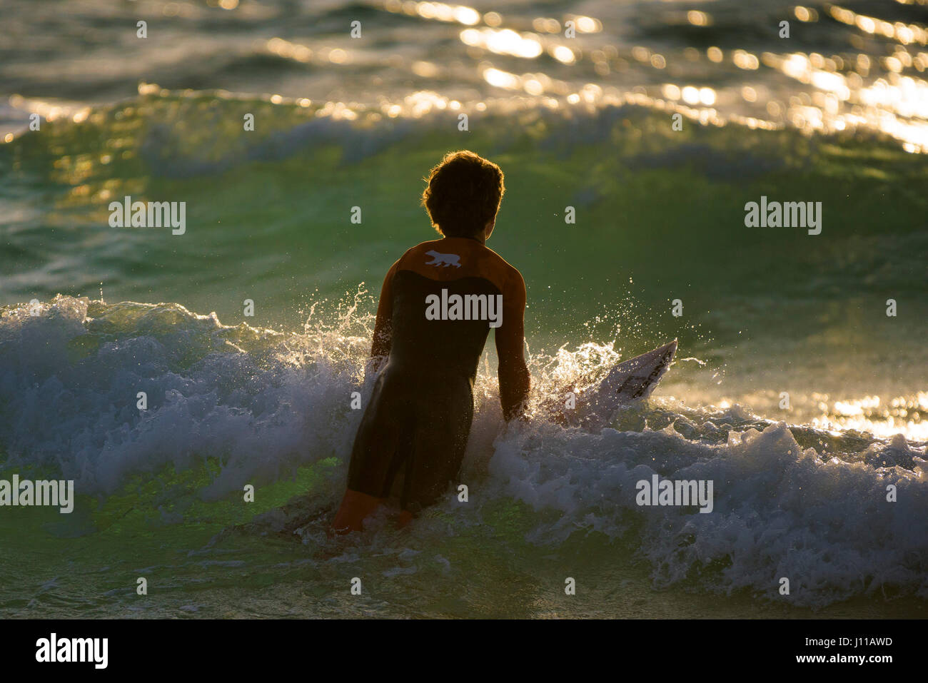 Surf Surfer Royaume-uni Cornwall Fistral vague surf board Paddling out à la mer les embruns Watersport Coucher du soleil le soir de l'activité physique Banque D'Images