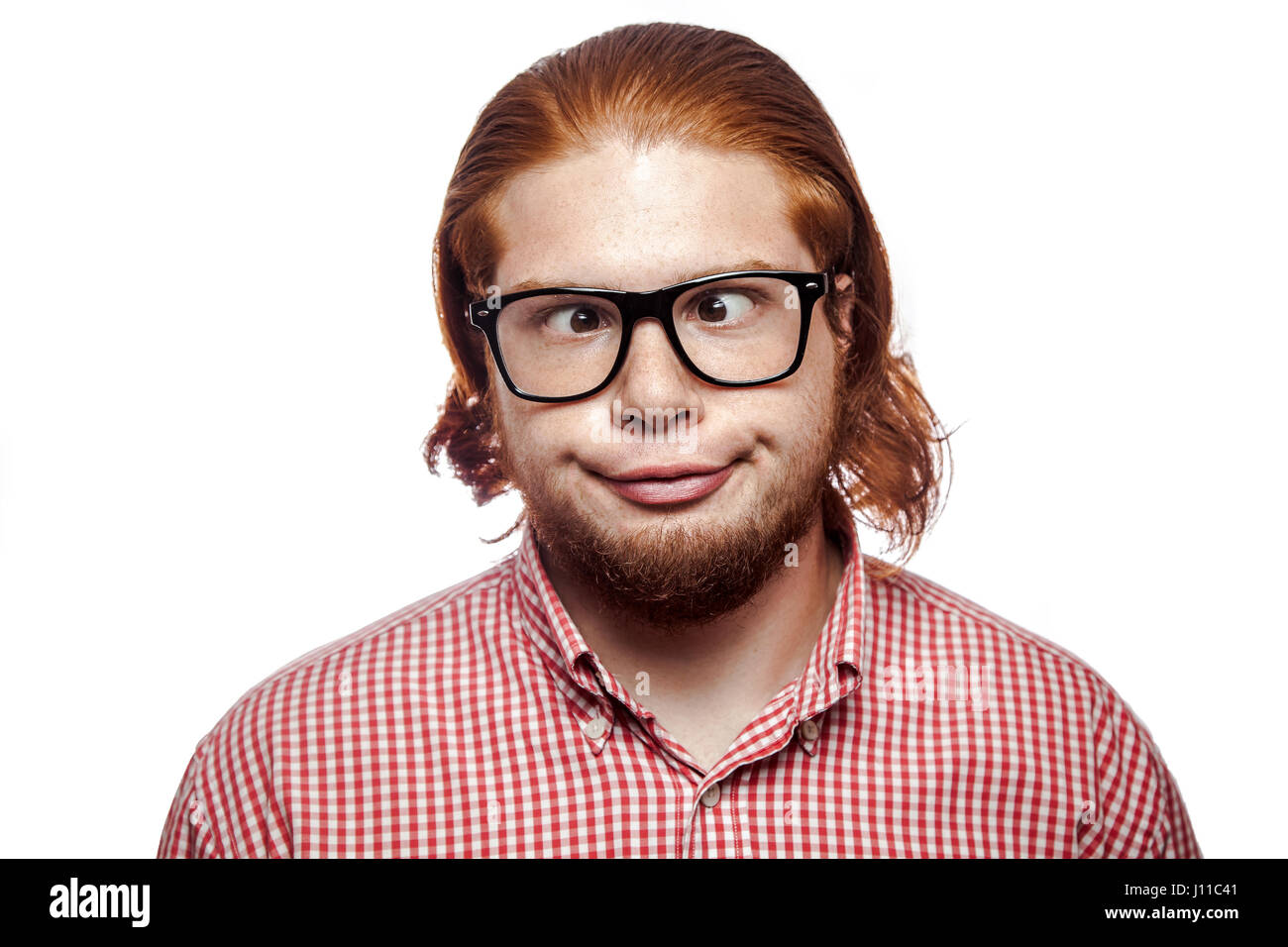 Carzy funny cross eyed businessman readhead barbu avec chemise rouge et les taches de rousseur et verres looking at camera. studio shot isolé sur blanc. Banque D'Images