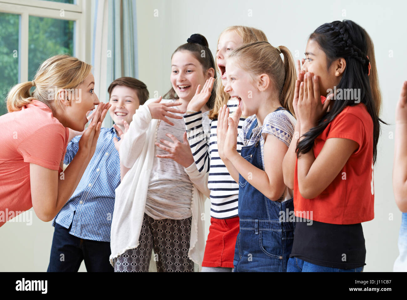 Groupe d'enfants avec l'enseignant bénéficiant d'ensemble de la classe d'Art Dramatique Banque D'Images