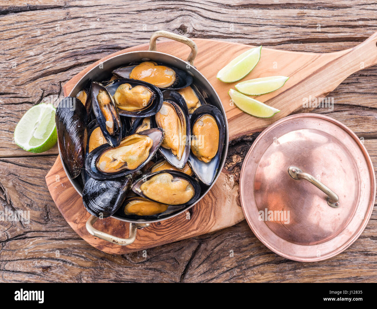 Les moules cuites en pan de cuivre sur la table en bois. Banque D'Images