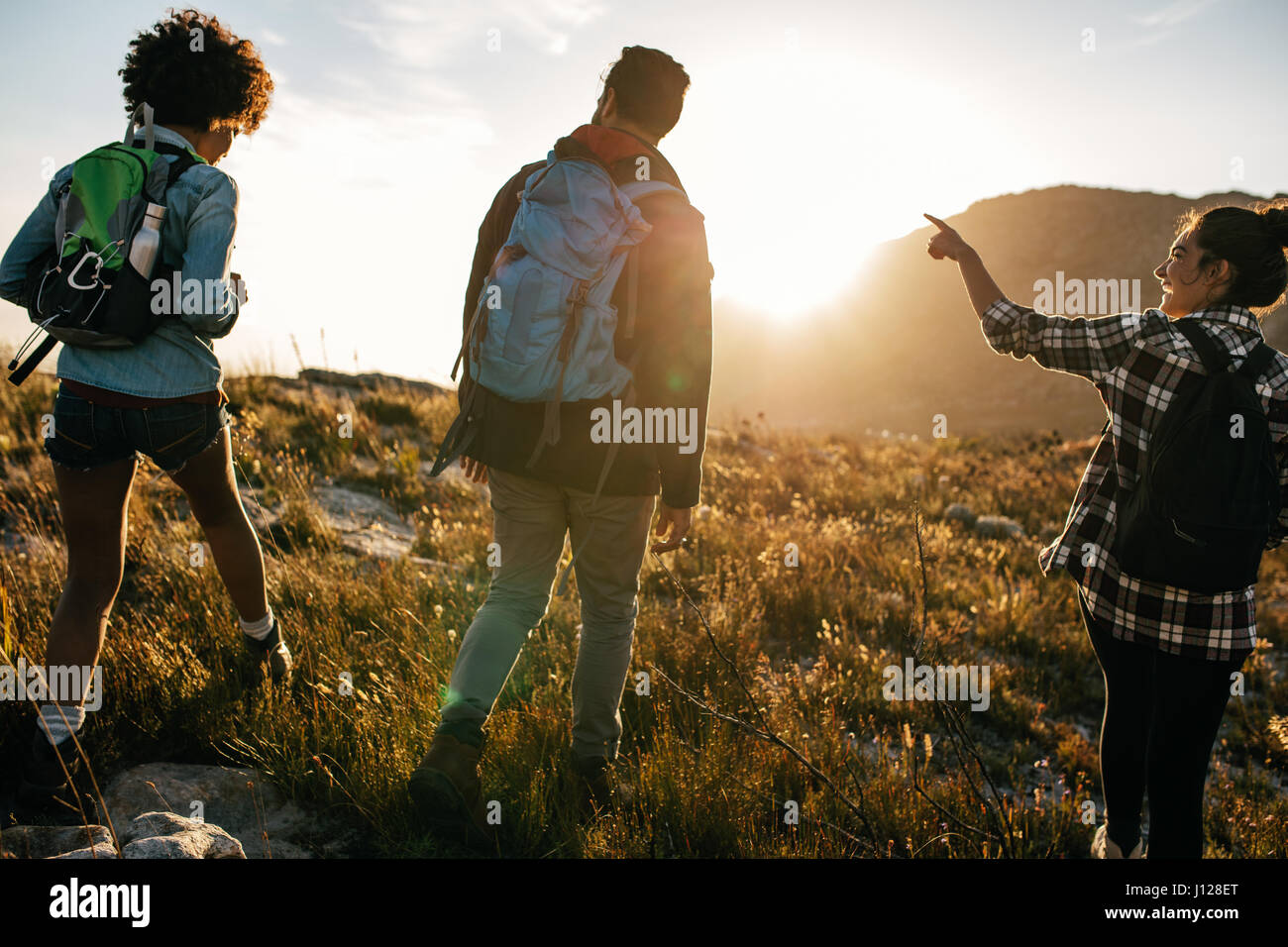 Vue arrière photo de jeunes sur campagne environnante de la randonnée. Groupe de randonneurs marchant sur hill un jour d'été. Banque D'Images