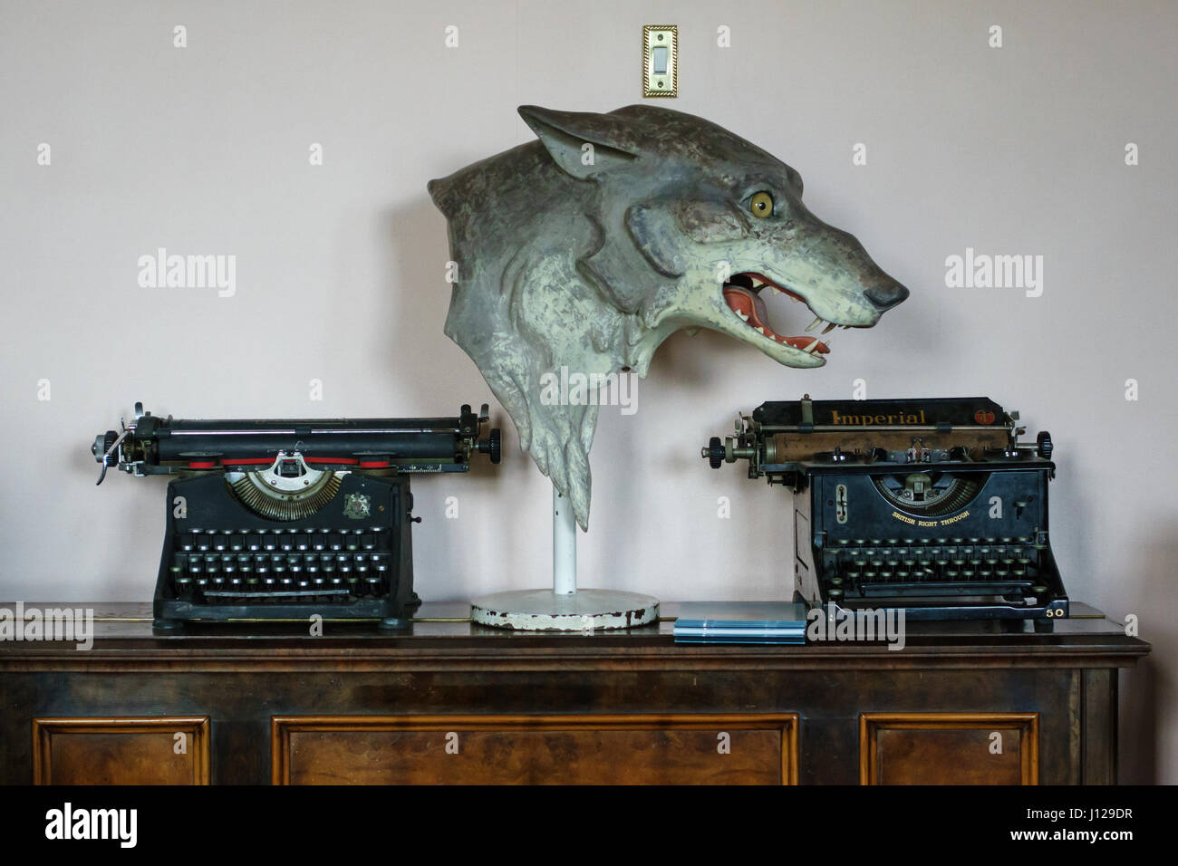 Une combinaison d'un surréaliste masque loup en caoutchouc entre deux vieux millésime à écrire dans une boutique Banque D'Images