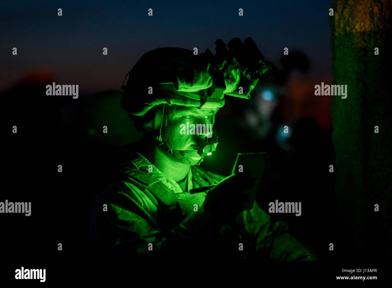 Un U.S. Marine avec 2e Bataillon, 6e Régiment de Marines utilise un feu vert pour lire ses notes pendant un raid huey lourd dans le cadre d'armes et tactiques cours instructeurs (WTI) 2-17 à Yuma (Arizona), le 12 avril 2017. L'exercice avait pour but de se concentrer sur l'exécution d'un assaut aérien de l'entreprise soutenu par raid et à voilure voilure fixe, d'escorte et stimulé les feux de l'aviation livré. Le WTI est une formation de 7 semaines organisé par Marine Aviation armes et tactiques d'un escadron (MAWTS-1), qui met l'intégration opérationnelle des six fonctions de Marine Corps à l'appui de l'aviation Banque D'Images