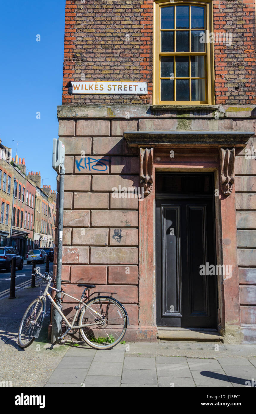 Une bicyclette appuyée contre un pilier en face de la porte à l'angle de la rue Wilkes dans l'Est de Londres. Banque D'Images