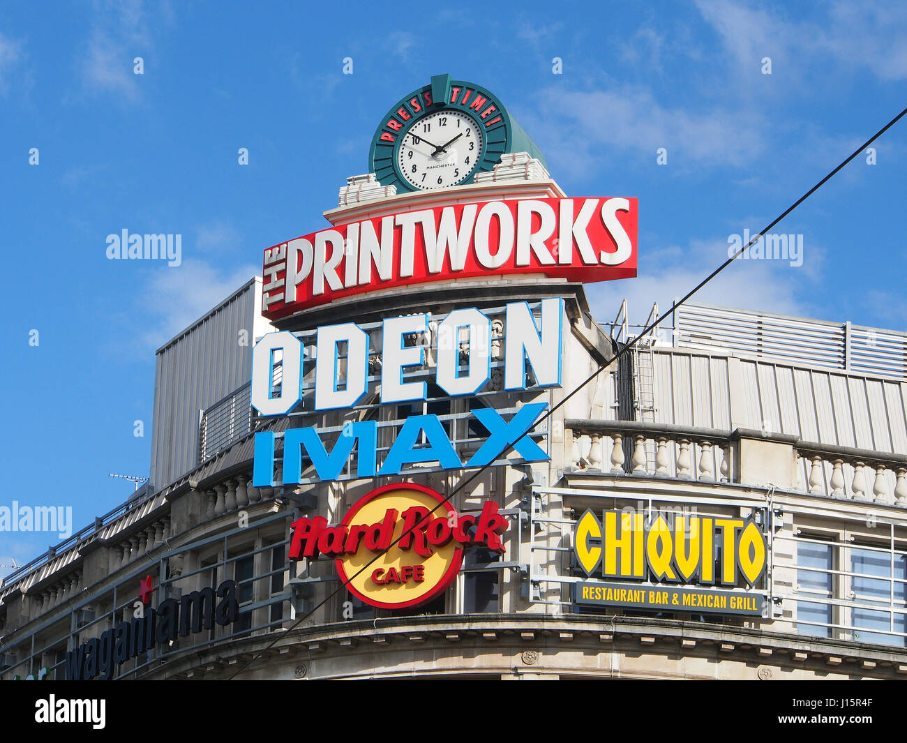 De l'extérieur de divertissement Printworks, dans le centre-ville de Manchester center, montrant tous les logos publicitaires colorés contre un ciel bleu. Banque D'Images