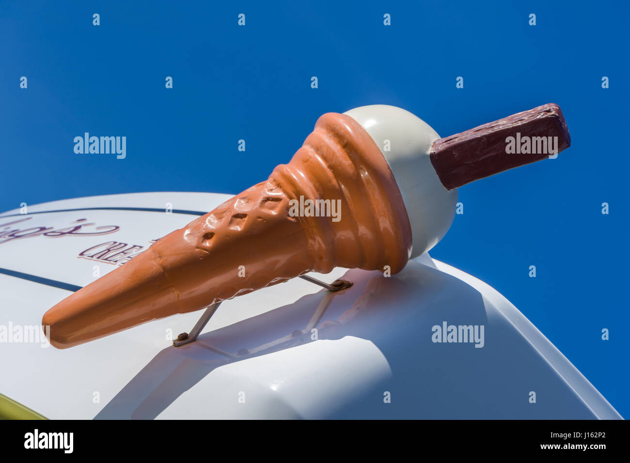 Un grand cornet de crème glacée en plastique se distingue d'un ciel bleu azur. Banque D'Images