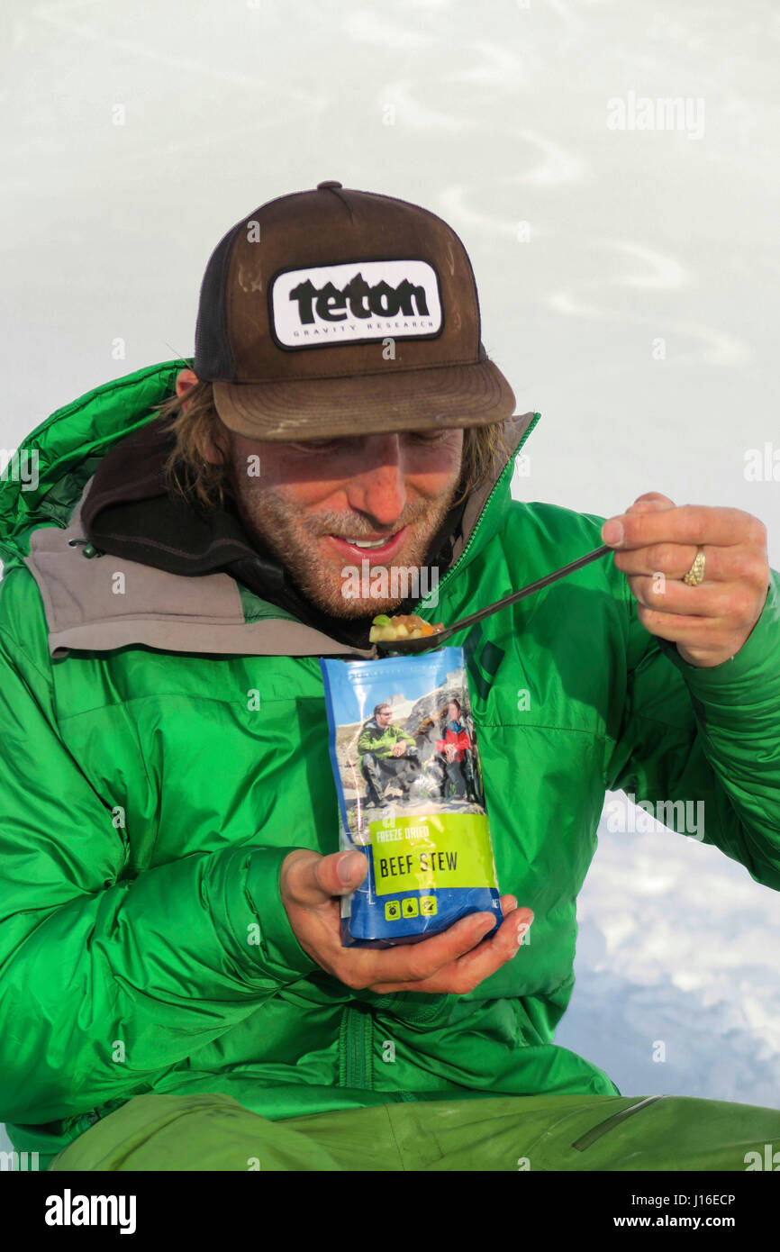 L'alpiniste de manger un sac de nourriture déshydratée sur Denali en Alaska Banque D'Images