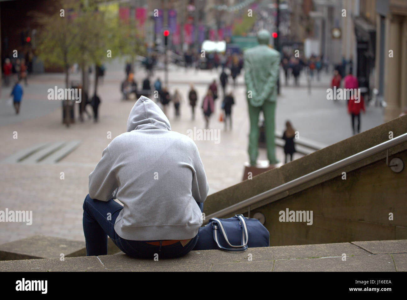 Jeune homme sweats sac de sport de Sport de s'asseoir sur le Glasgow concert hall comme suit à la jonction de Buchanan Street et Sauchiehall Street Banque D'Images