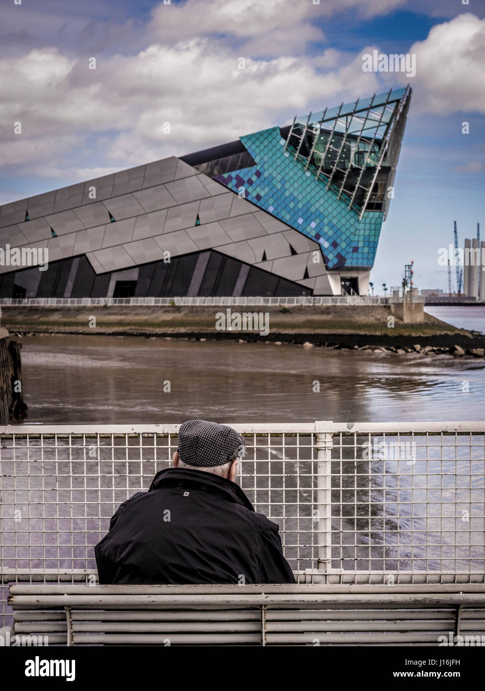 Old man wearing flat cap assis sur un banc à la recherche sur l'eau à la profondeur, une attraction touristique, Hull, Royaume-Uni. Banque D'Images