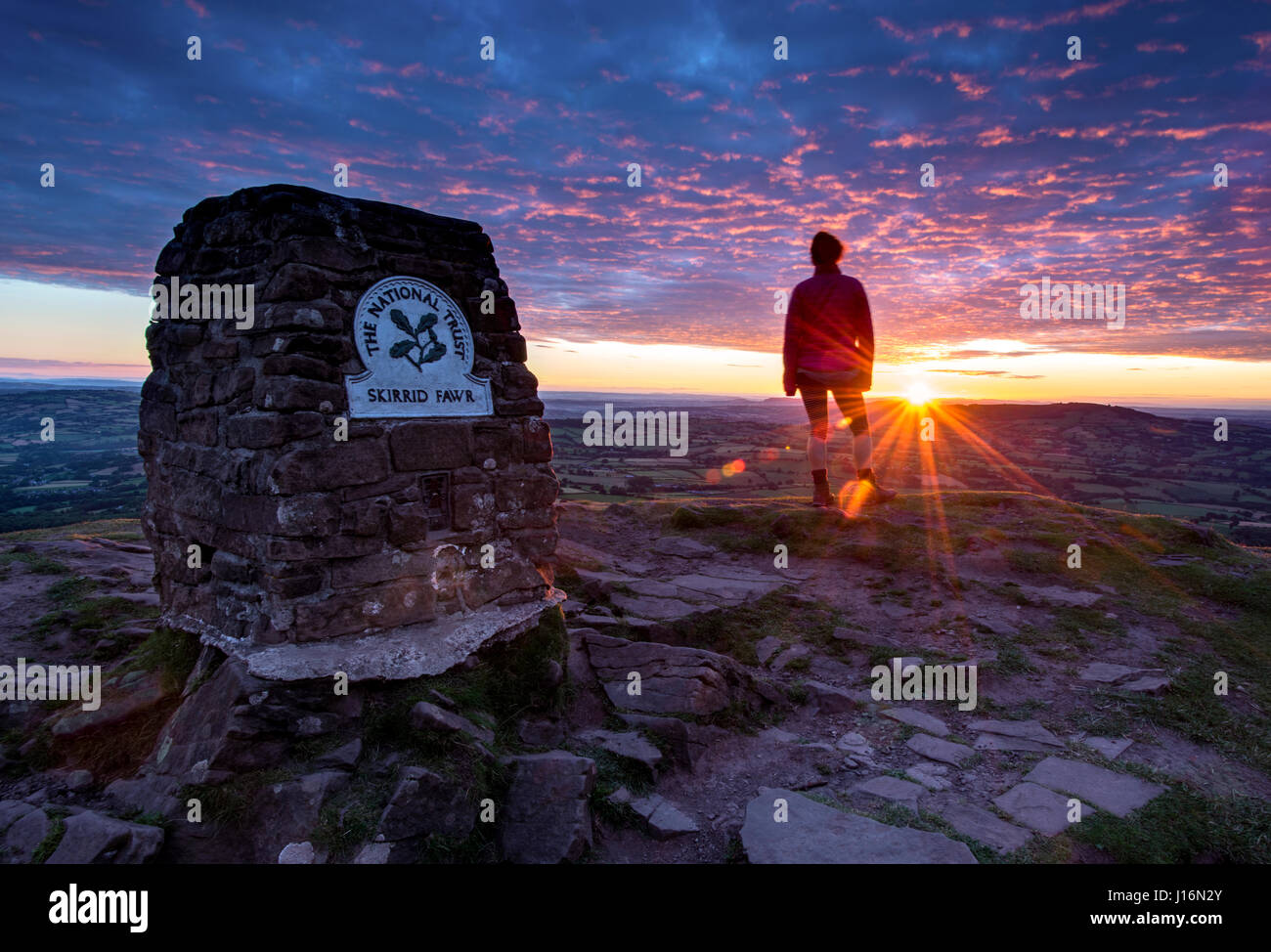 Femme mature à la recherche au lever du soleil sur la montagne Skirrid dans les Montagnes Noires, Brecon Beacons National Park, au Pays de Galles Banque D'Images