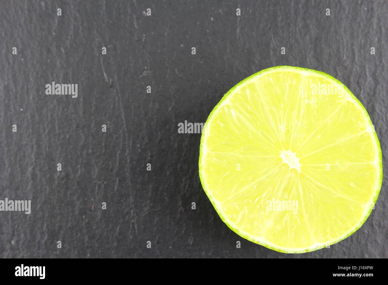 Fruits de citron vert frais sur une plaque en ardoise comme une texture de fond de l'alimentation Banque D'Images