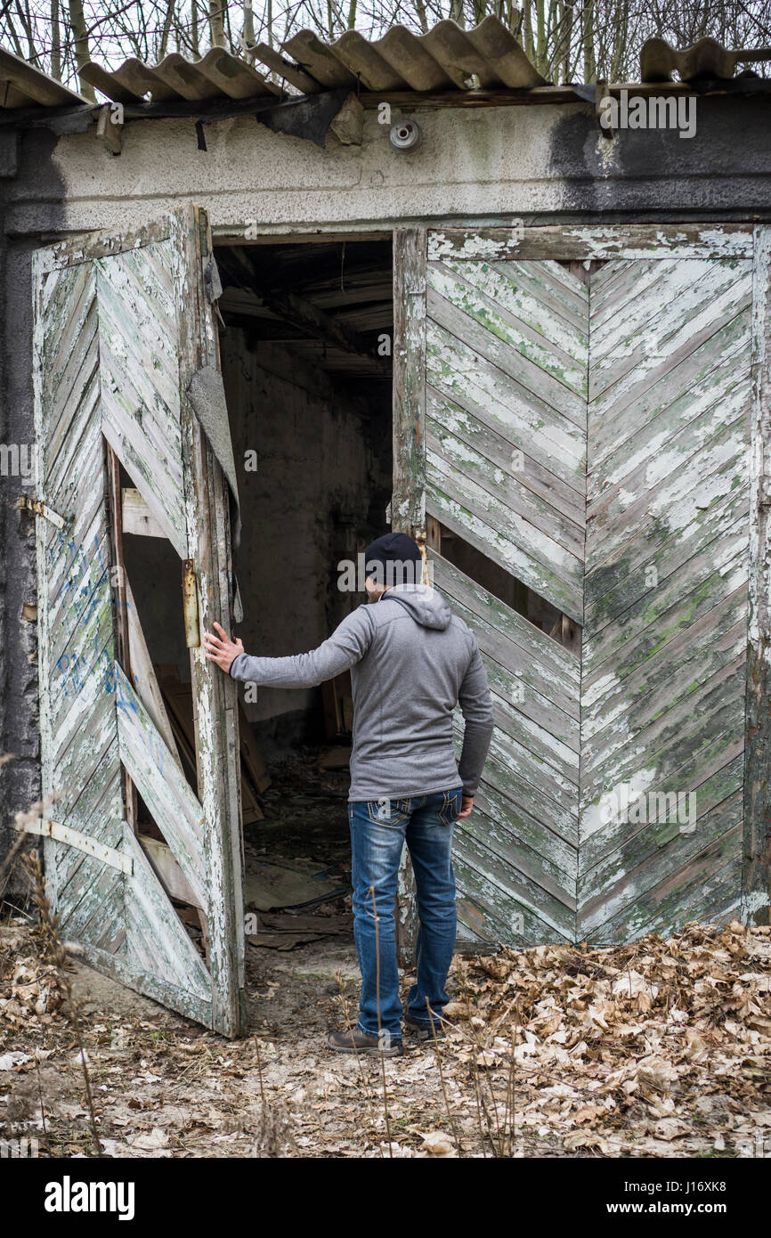 Vue arrière d'un homme de l'ouverture d'un déserté derlict barn Banque D'Images