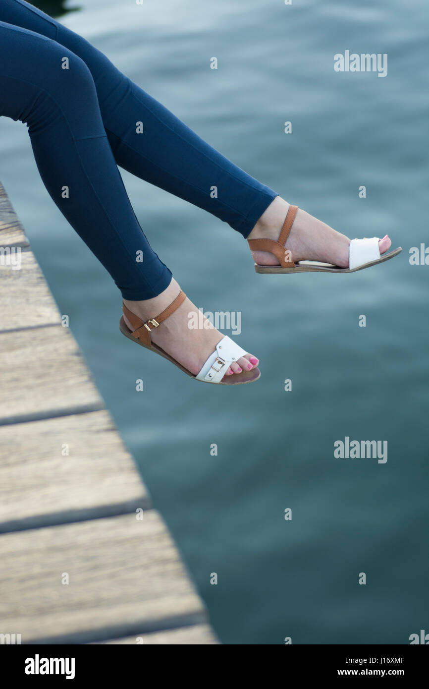 Close up of a woman's legs assis sur le quai par la mer Banque D'Images
