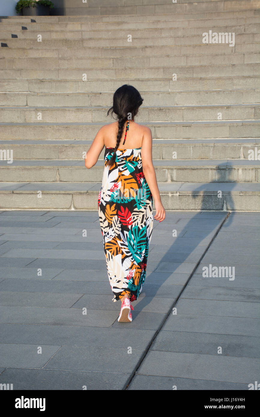 Vue arrière d'une jeune femme portant une robe d'été en montant les escaliers à l'extérieur Banque D'Images