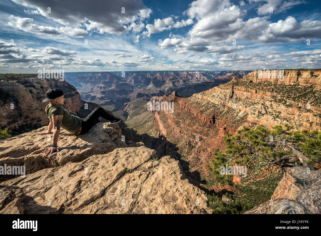 Grand Canyon et un jeune randonneur assis sur la jante et profiter de la vue. Banque D'Images